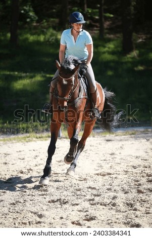 Rider with brown horse galloping during the support phase, picture upright.