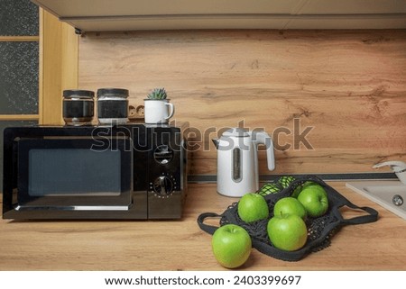 kitchen stove. wooden wall in the kitchen. white kettle and black microwave. equipment of kitchen. isolated green apple on table. design and interior of modern room in apartment flat. breakfast tea 