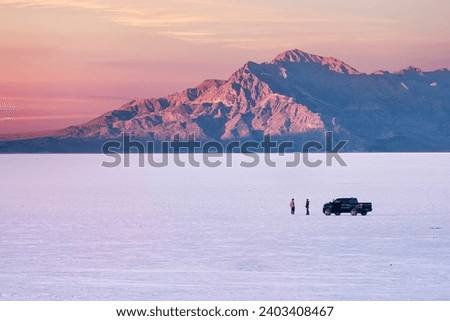 Two people with car on Salt Flats near Salt Lake City at sunset. Utah. USA Royalty-Free Stock Photo #2403408467
