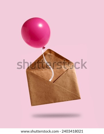 Craft paper envelope with pink air balloon on pink background. 