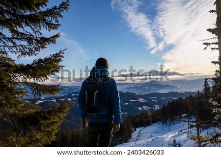 Backpack man with scenic view of Lavant valley and Koralpe in Carinthia, Styria, Austria. Winter wonderland in Austrian Alps. Ski touring in snow covered landscape. Hiking trail to Forstalpe
