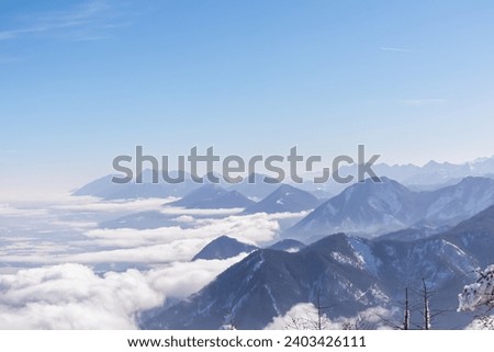 Panoramic aerial view of snow capped mountain ranges of Karawanks, Julian and Kamnik Savinja Alps in Carinthia, Austria. Winter wonderland in remote Austrian Alps. Valley covered with mystical fog