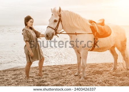 A white horse and a woman in a dress stand on a beach, with the