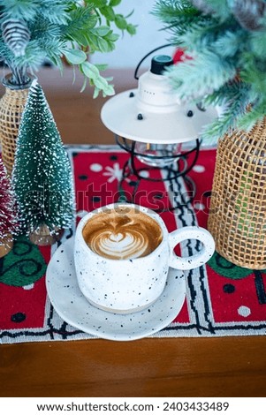 Close up of Hot coffee latte with latte art milk foam in cup mug with Xmas decors and Xmas tree baubles on wood desk Celebrating Merry Christmas and New year.