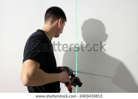 A young man drills holes in the wall with a hammer drill. The master works with a hammer drill. Renovation concept. Royalty-Free Stock Photo #2403433813