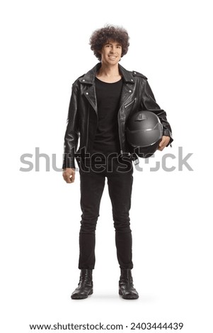 Full length portrait of a young man in a leather jacket holding a helmet and smiling isolated on white background