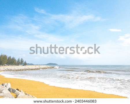 The beautiful beach with a wave of the sea and the clear blue sky with whire clouds.