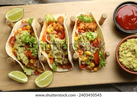 Delicious tacos with guacamole, meat and vegetables served on table, top view