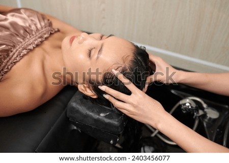 Hairdresser washing hair of client with deep cleaning shampoo to remove excess buildup Royalty-Free Stock Photo #2403456077