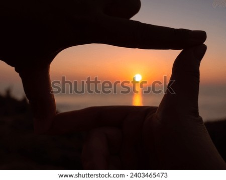 Picture of the sunset in a finger frame.