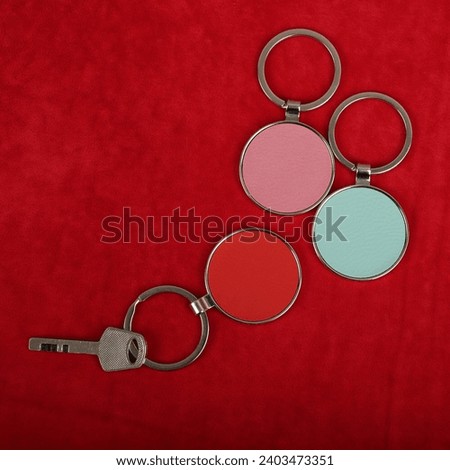 Metal and leather keychains. Colorful one side leather; Square, rectangle and circle shaped key rings. Concept shots, photos taken specially for e-commerce sales. Red fabric background.