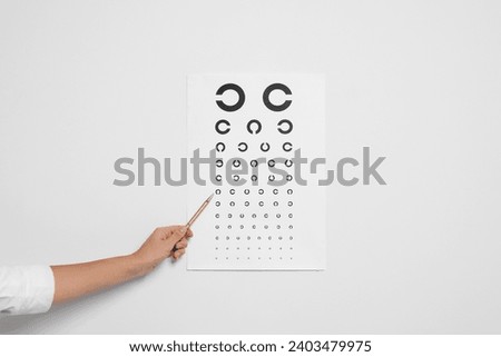 Ophthalmologist pointing at vision test chart on white background, closeup Royalty-Free Stock Photo #2403479975