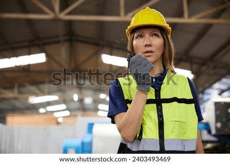 female worker talking on walkie talkie in the factory Royalty-Free Stock Photo #2403493469