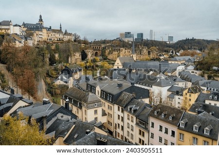 Panoramic view of Luxembourg city on a cloudy winter day. Church and private buildings with dark steep rooftops. Mist and clouds over the city.