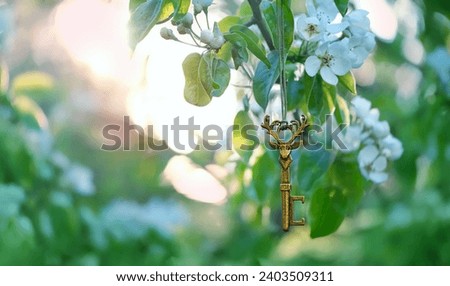 spring nature background. vintage key with deer shape on blossom spring tree, sunny green backdrop. magical key-amulet, symbol of secret garden, soul of forest. spring season floral image