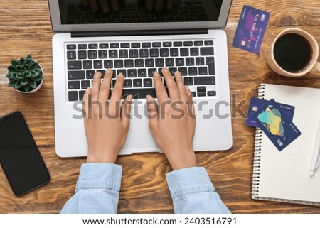 Woman with laptop and credit cards shopping online on wooden background