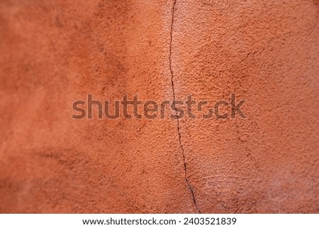 Close-up at orange pastel roughly  concrete wall with cracked line on surface. Background and texture photo.