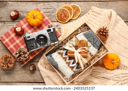 Beautiful composition with warm socks and photo camera on wooden background