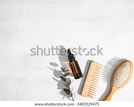 Essential oil for hair care with wooden hair comb and bamboo comb on white background top view, flat lay. copy space. Self care, hair treatment concept. Royalty-Free Stock Photo #2403529471