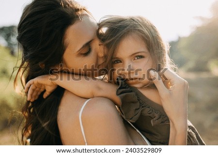 Closeup calm portrait of a mother holding her little daughter in arms, outdoors. Royalty-Free Stock Photo #2403529809