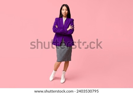 Portrait of young Asian businesswoman with crossed arms on pink background