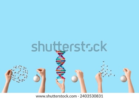 Hands holding Christmas decorations, DNA and molecule models on blue background