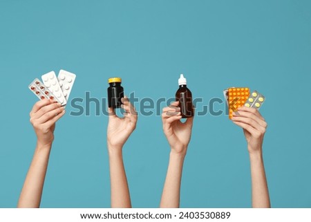 Female hands holding pills in blister packs and medicines on blue background
