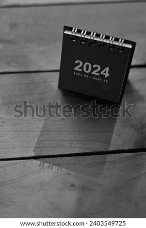 close up red 2024 small calendar on wood table, planning and manage time to success business, holiday season and happy new year wallpaper background concept, black and white tone