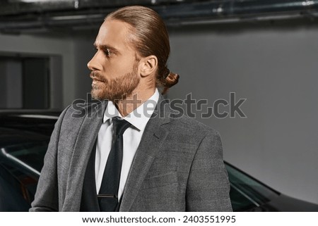 handsome red haired man with ponytail in elegant suit posing and looking away, business man Royalty-Free Stock Photo #2403551995