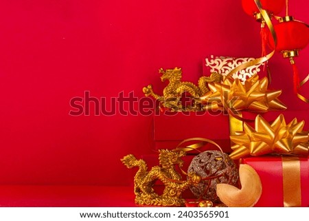 Chinese New Year 2024 greeting card. Bright red asian year of the dragon background with golden dragon figurine, Chinese lanterns, traditional jewelry, gifts, coins, cookies with wishes, copy space