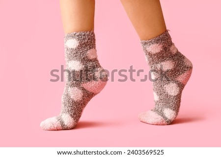 Legs of young woman in warm grey dotted socks on pink background Royalty-Free Stock Photo #2403569525