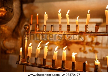 Lit candles on an ornate stand, offering a warm, tranquil glow for spiritual or religious observance Royalty-Free Stock Photo #2403570197