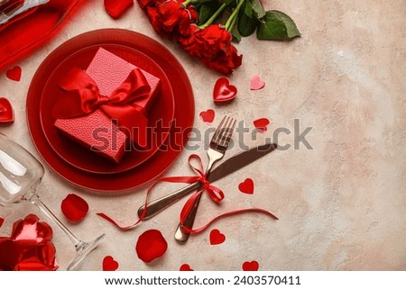 Beautiful table setting for Valentine's Day with wine bottle, red roses and decor on beige grunge background Royalty-Free Stock Photo #2403570411