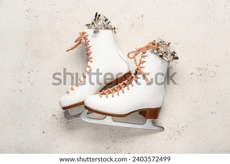White ice skates with Christmas tinsel on light background