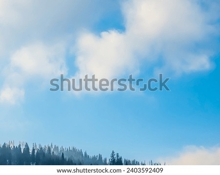 In the blue sky, beautiful white cumulus, stratus and cirrus clouds create a harmonious canvas over the mountains. The dynamic interaction of cloud formations adds elegance to serene spaces.