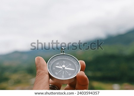 close up hand holding compass with mountain and sky background, travel and relaxation, planning and manage to success business concept