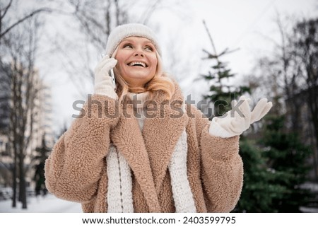 Photo of charming dreamy woman wear beige coat talking modern device choosing new year tree outside urban city park