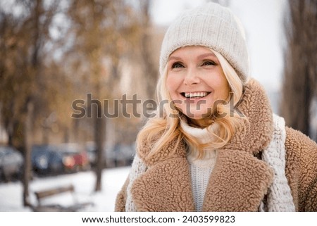 Photo of positive adorable retired woman spending weekend time in snowy forest cold outside