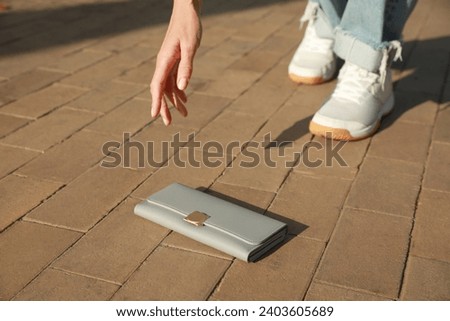 Woman picking up grey purse outdoors, closeup. Lost and found Royalty-Free Stock Photo #2403605689