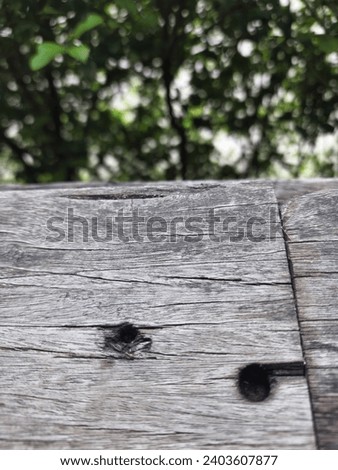 Old wooden fence with green bushes in the background.