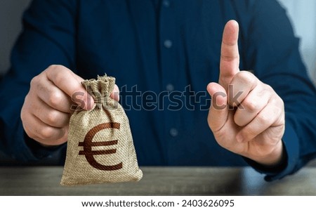 A man warns with his finger offering a euro money bag. Bad credit history. Funding and grants. Banks and finance. Terms of borrowing money. Strict conditions. Loan for a specific purpose. Royalty-Free Stock Photo #2403626095