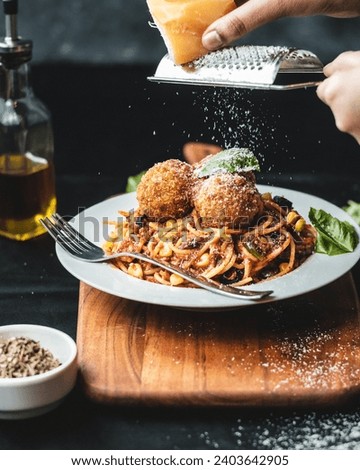 spaghetti and cheeseballs picture served in a white plate, garnished with parmesan and basil