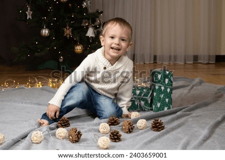 Cheerful little boy near Christmas tree at home