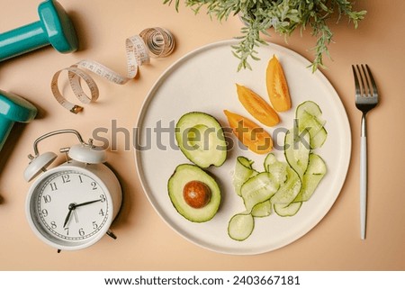 Creative flat lay composition with plate, alarm clock, knife, fork, dumbbell and measuring tape on pink background. Intermittent fasting, ketogenic, diet concept. top view, copy space.
