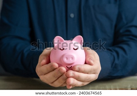 A calmly sleeping piggy bank in the hands. Trust fund. A reliable way to store savings and passive income. Savings and deposit banking. Wealth and prosperity. Successful investments and deposits. Royalty-Free Stock Photo #2403674565