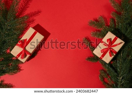New Year's gifts are wrapped in festive kraft paper and red ribbon. A Christmas tree with gifts. Red background.