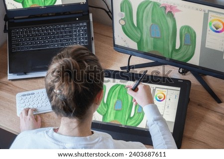 Young woman drawing on a digital tablet. Female graphic designer working from home. Girl drawing on a digital drawing board, view from behind