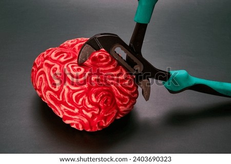 Red brain compressed by pliers. Concept of mental stress. Royalty-Free Stock Photo #2403690323