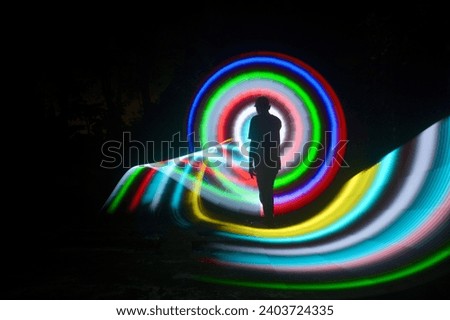one person standing against beautiful blue and red circle light painting as the backdrop
