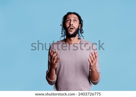 Arab person begging for forgiveness with emotional facial expression and open hands. Religious young man pleading for god blessing and believe while looking upwards concept